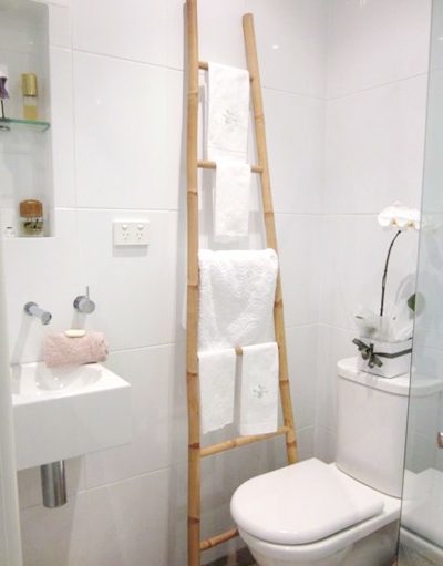 Nếu không muốn đóng thêm tủ cho phòng tắm chật, bạn có thể sử dụng chiếc thang tre để treo khăn.